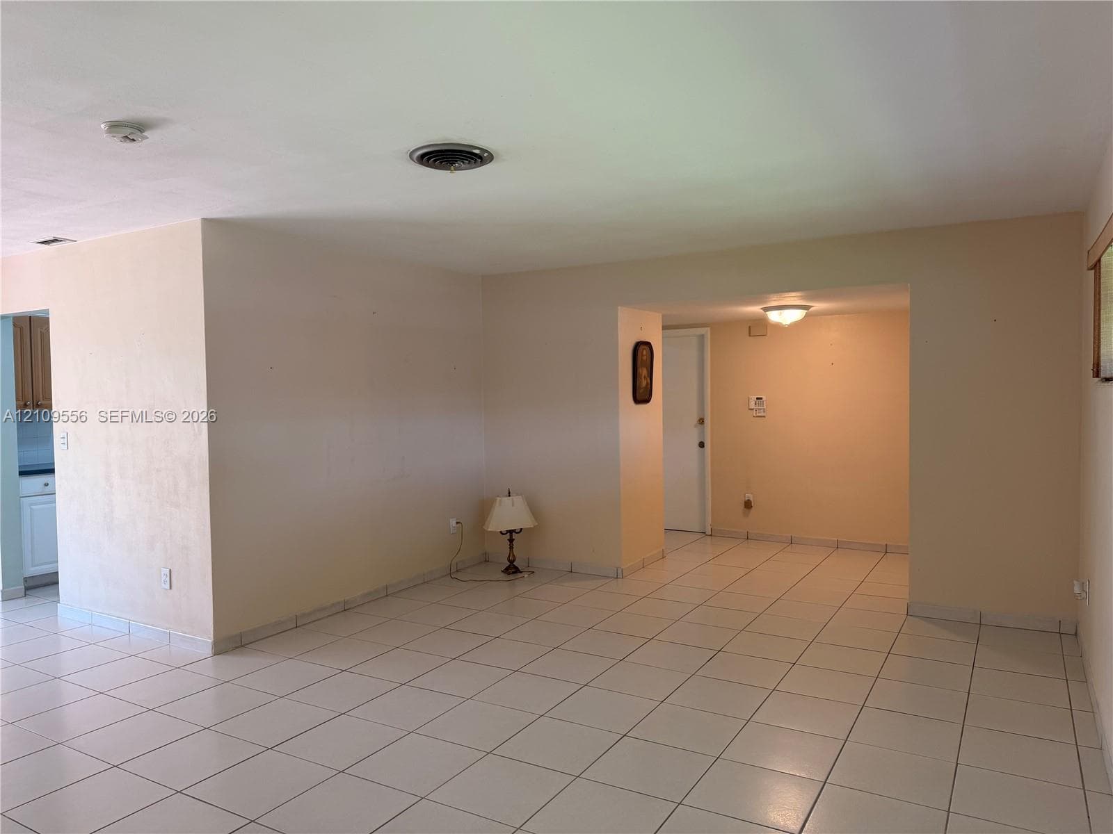 Neutral-toned interior space featuring ceramic tile flooring, a flush-mount ceiling light fixture, and white interior doors