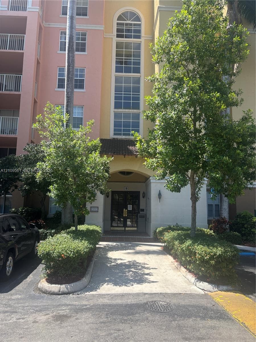 Multi-story exterior featuring arched windows, vertical glass paneling, tile roofing, and a recessed entryway