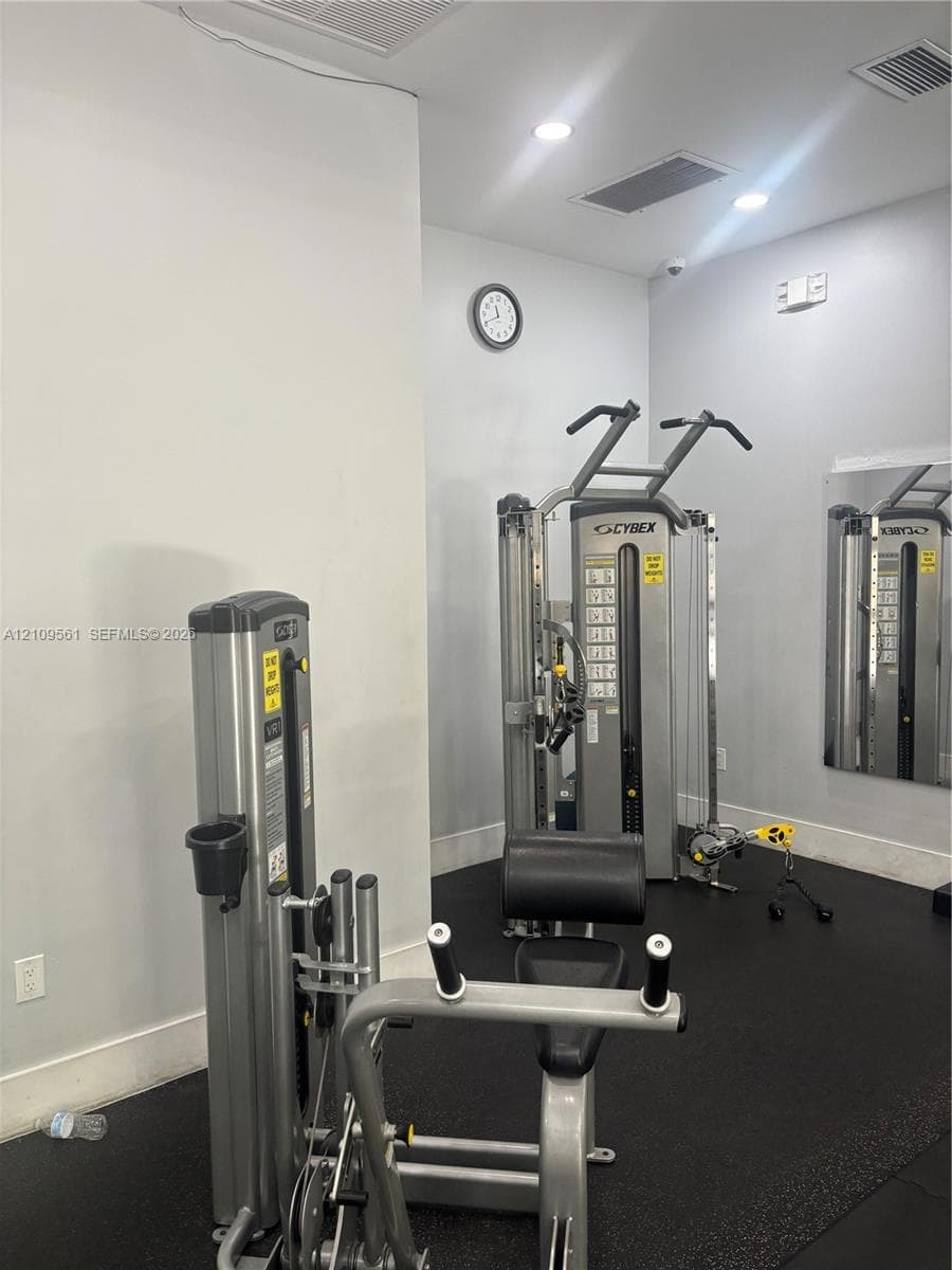 Fitness area featuring rubber flooring, recessed ceiling lighting, and wall-mounted mirrors