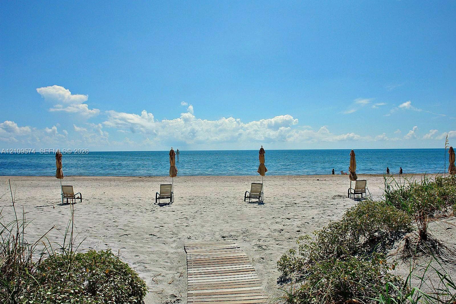 Sandy beach frontage with native dune vegetation and a wood-slat boardwalk path
