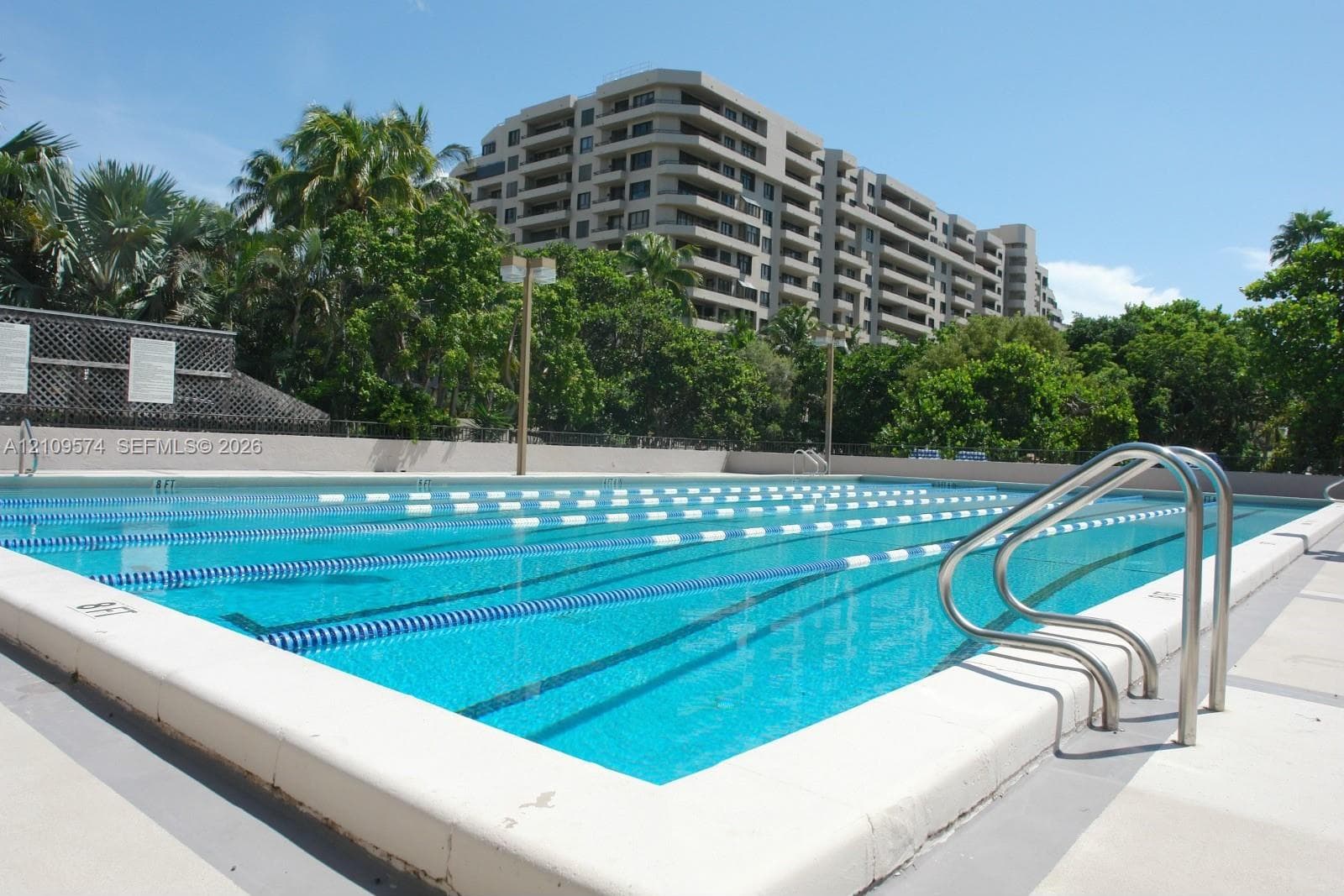 Multi-lane lap pool featuring metal entry railings, lane markers, and a concrete pool deck