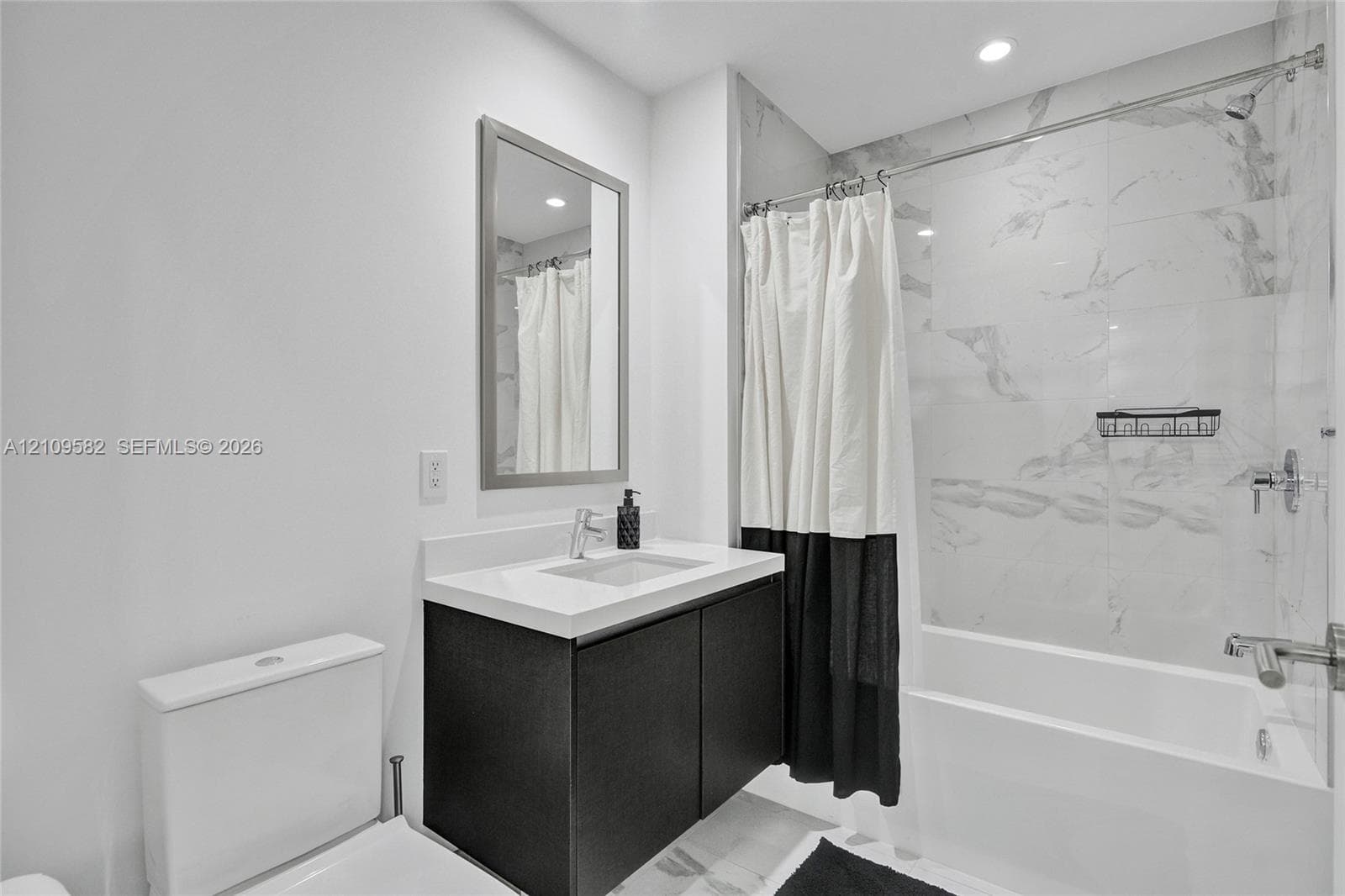 Floating vanity with a white countertop and rectangular basin, full-height wall tiling in the shower area, and recessed ceiling lighting