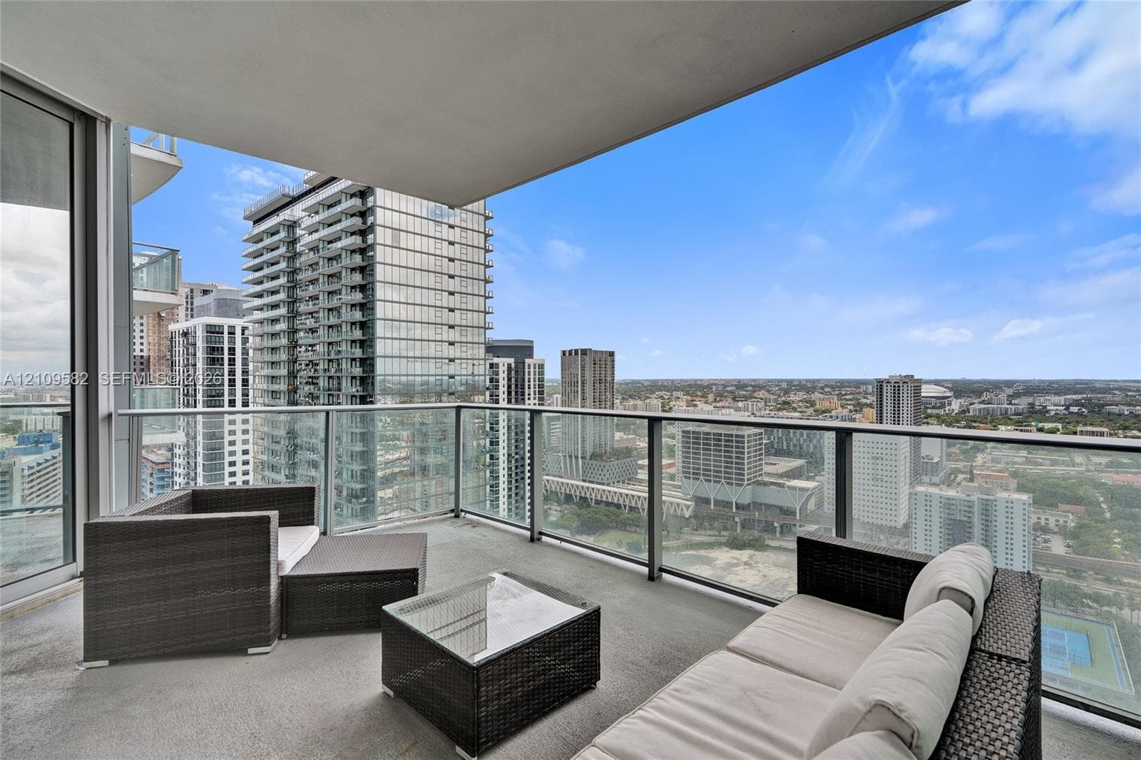 Covered balcony featuring concrete flooring and a glass-paneled railing