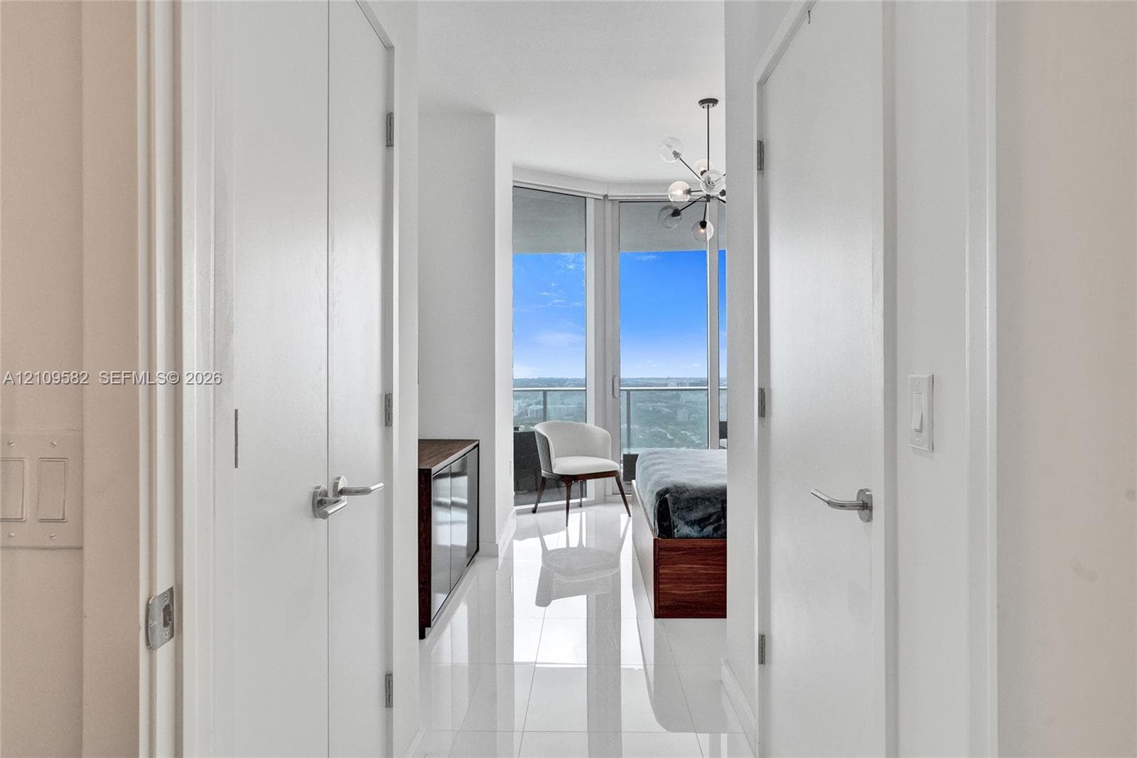 Floor-to-ceiling windows, polished tile flooring, multi-arm chandelier, and double-closet configuration