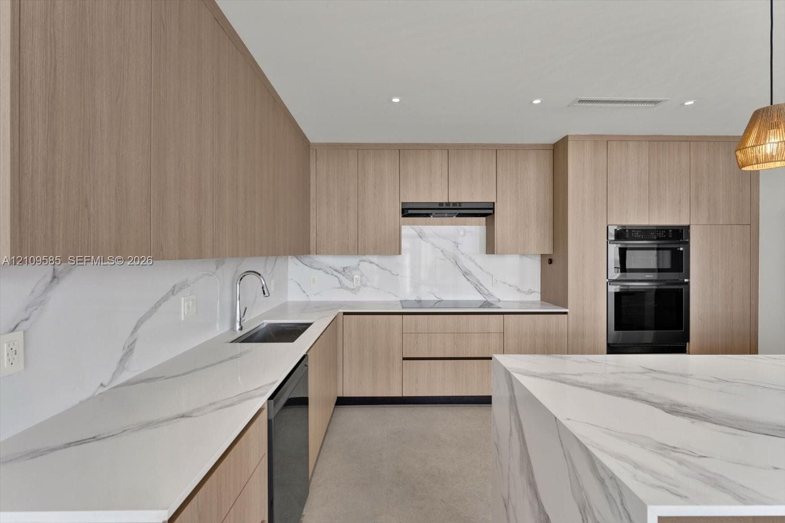 Kitchen featuring flat-panel wood-finish cabinetry, waterfall-edge stone countertops, matching stone slab backsplash, stainless steel built-in double oven, and recessed lighting