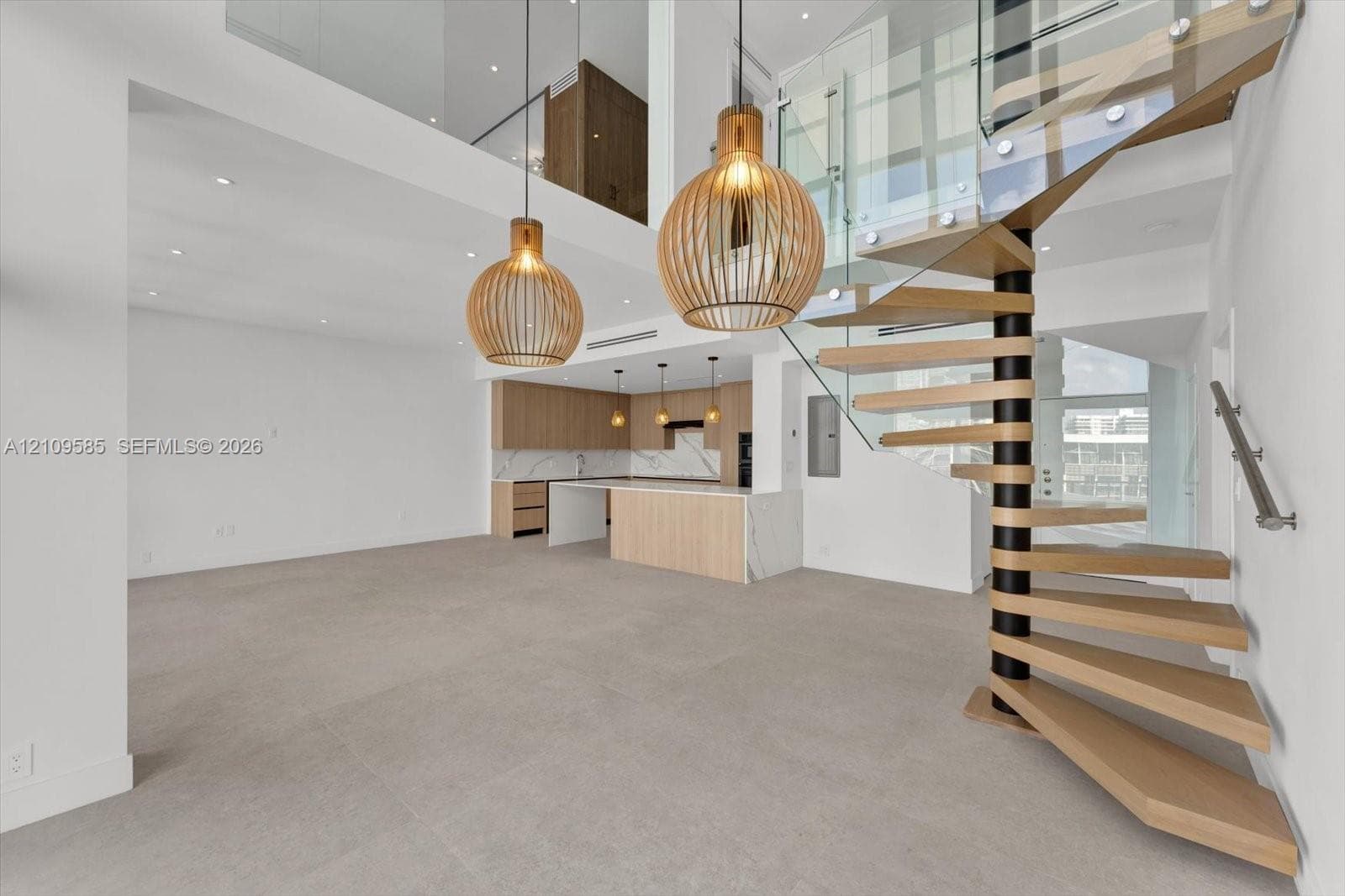 Spiral staircase featuring wooden treads and a glass railing, complemented by two large cage-style pendant lights, light wood-finish cabinetry, stone countertops, and tile flooring