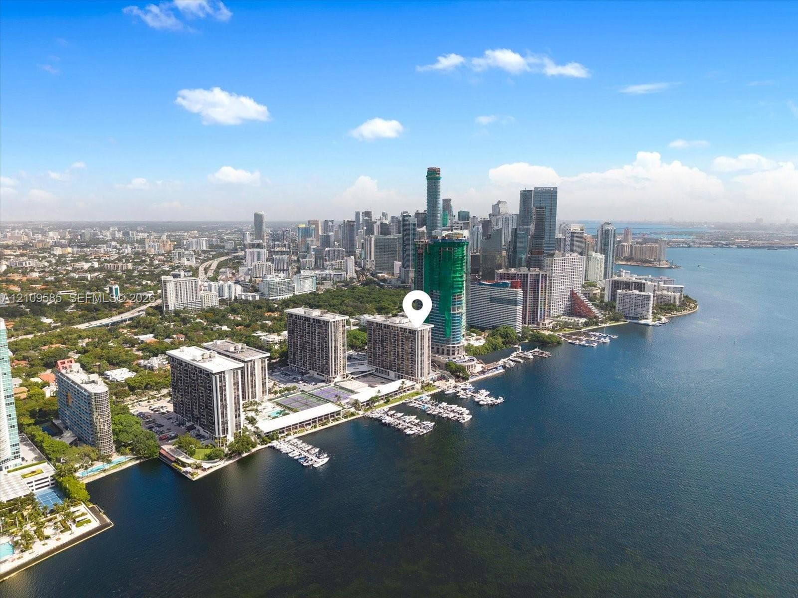 Aerial perspective of waterfront high-rise property featuring deep-water marina access, proximity to metropolitan skyline, and direct coastal frontage