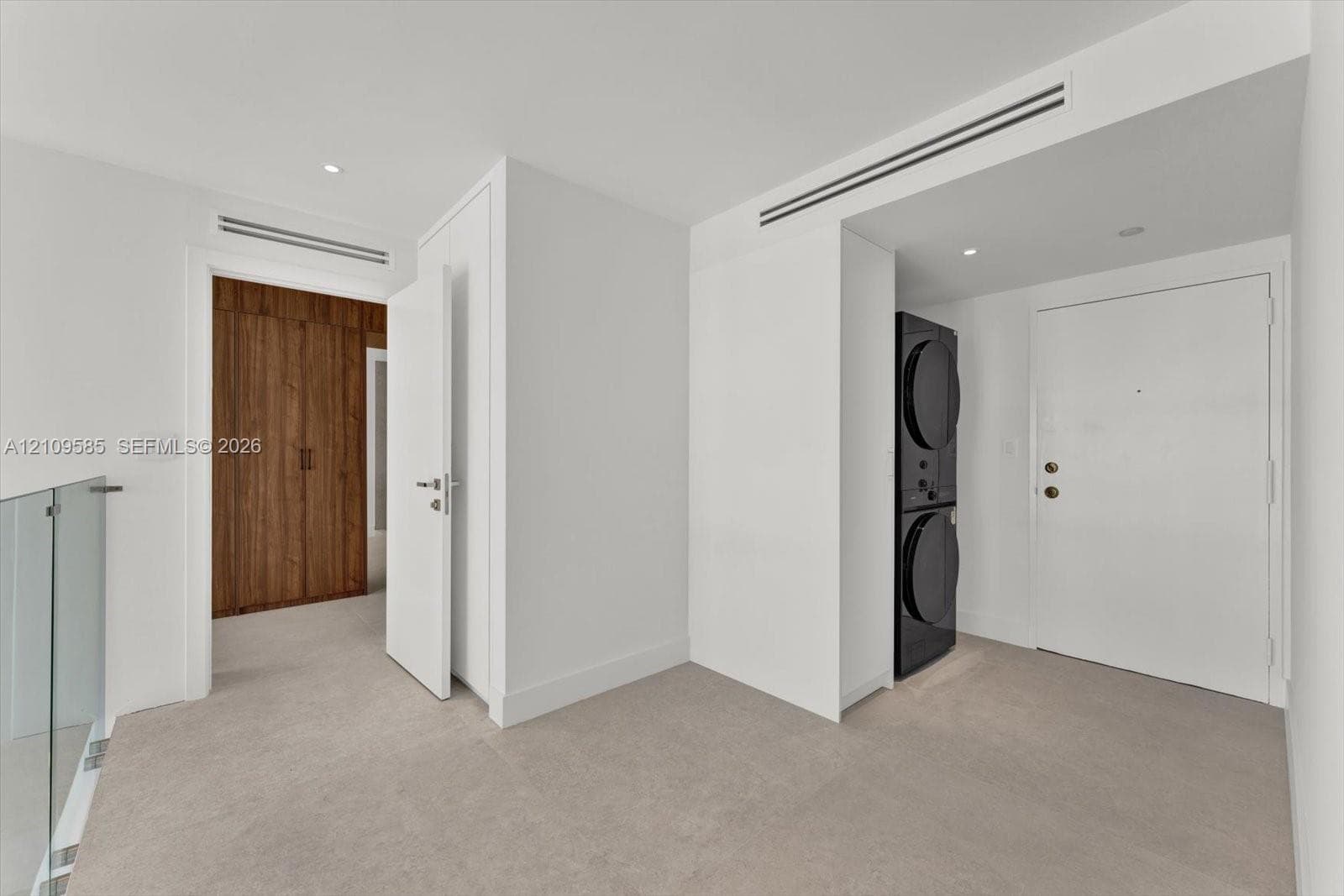 Stacked laundry unit, full-height wood-finish cabinetry, recessed ceiling lighting, and glass panel railing