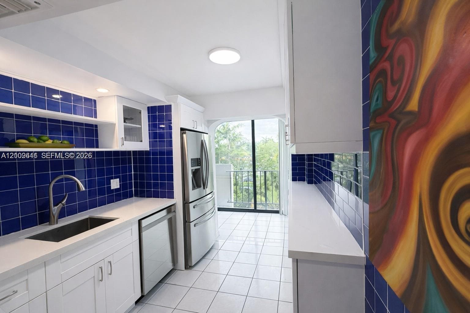 Kitchen featuring white cabinetry, quartz countertops, blue tile backsplash, stainless steel appliances, and tile flooring