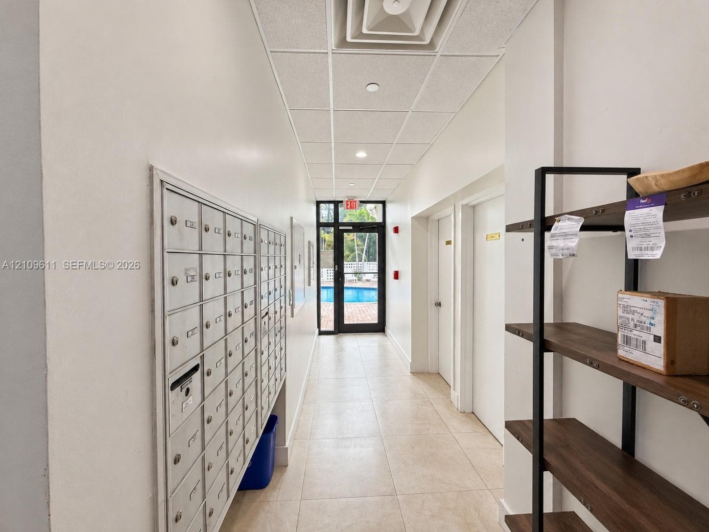 Hallway featuring tile flooring, a drop ceiling, and integrated postal boxes