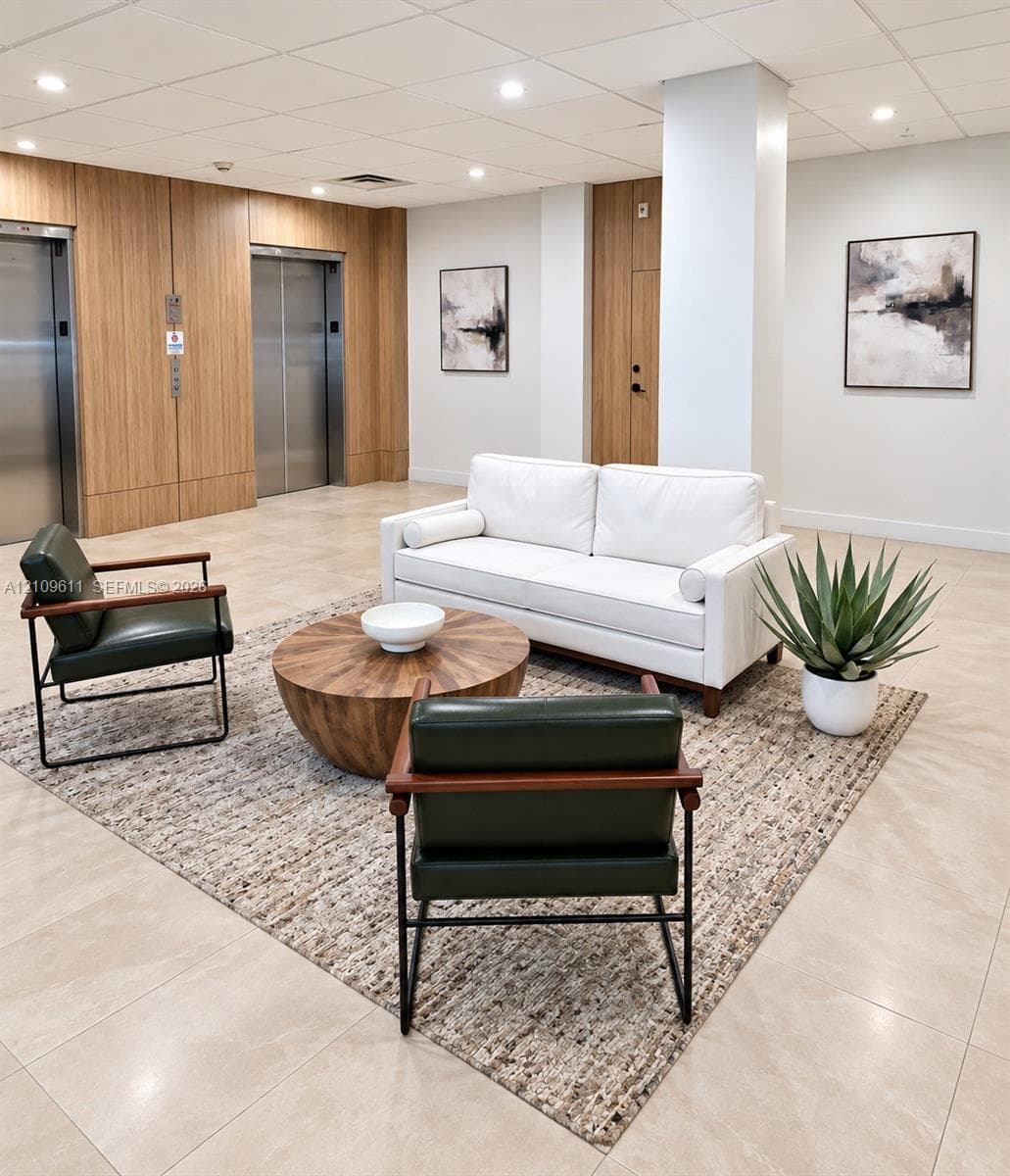 Lobby area featuring dual stainless steel elevators, wood-finish paneling, tile flooring, and recessed ceiling lighting