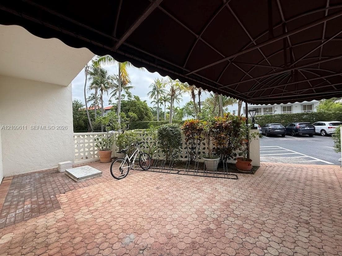 Covered entryway featuring a metal frame awning, interlocking paver flooring, and decorative concrete screen wall
