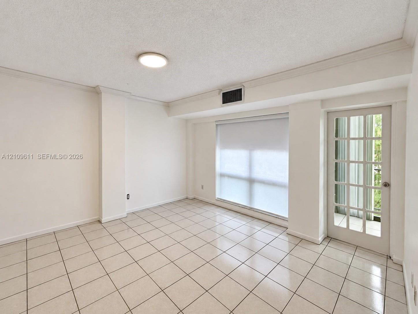 Large-format tile flooring, French-style glass door, and expansive window with roller shade