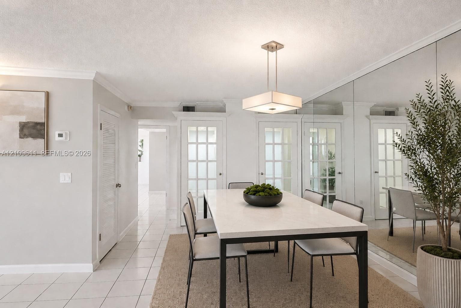 Dining space featuring floor-to-ceiling mirrored walls, a square brushed-nickel pendant light, and triple French doors with glass panes