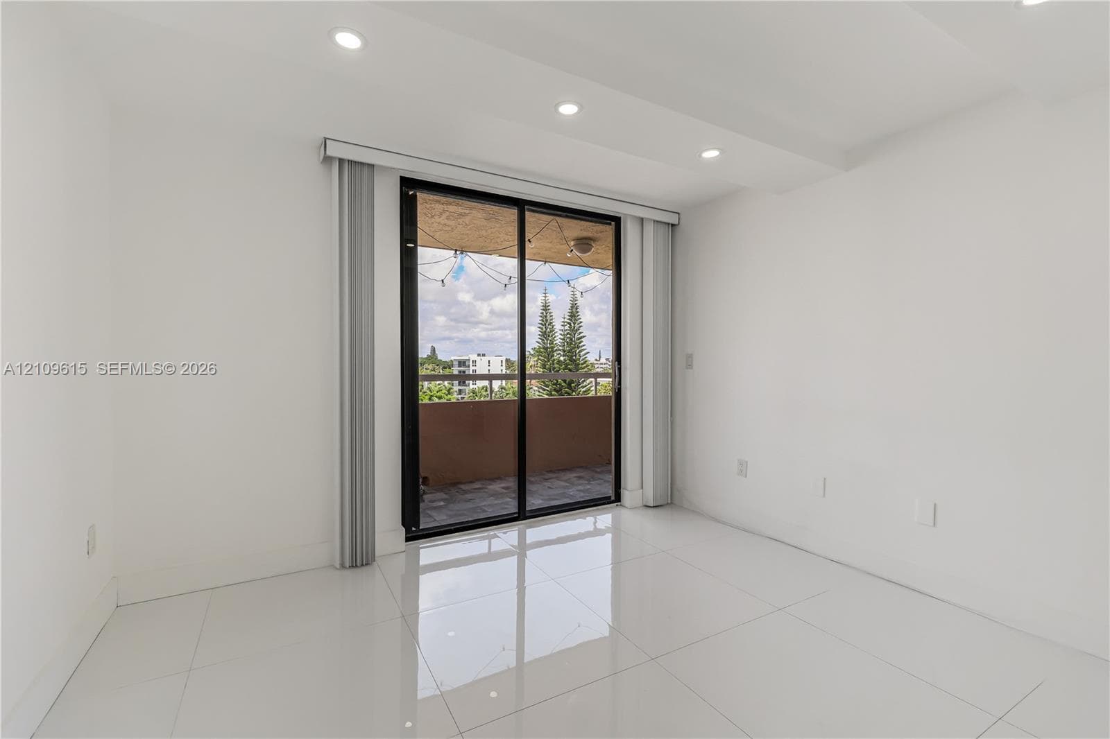 Interior space featuring polished tile flooring, recessed lighting, and a sliding glass door providing external access to a private balcony