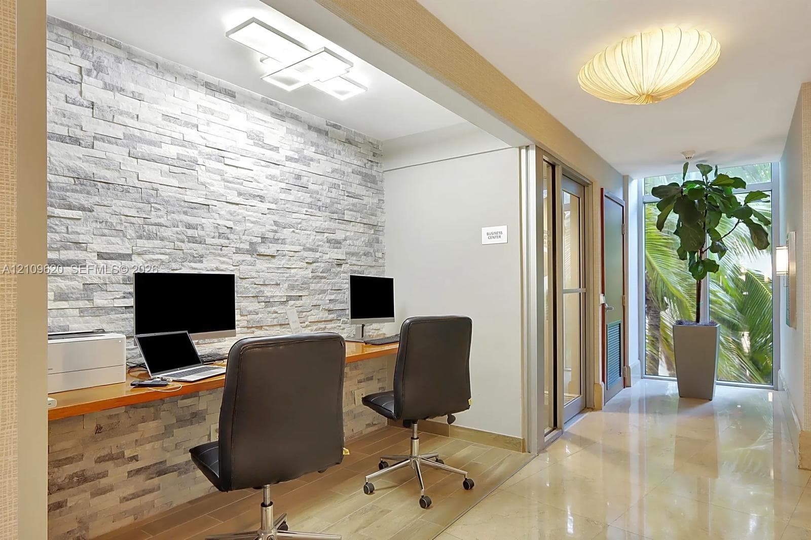 Textured stone accent wall, integrated built-in wood desk, polished tile flooring, contemporary flush-mount lighting, and floor-to-ceiling windows