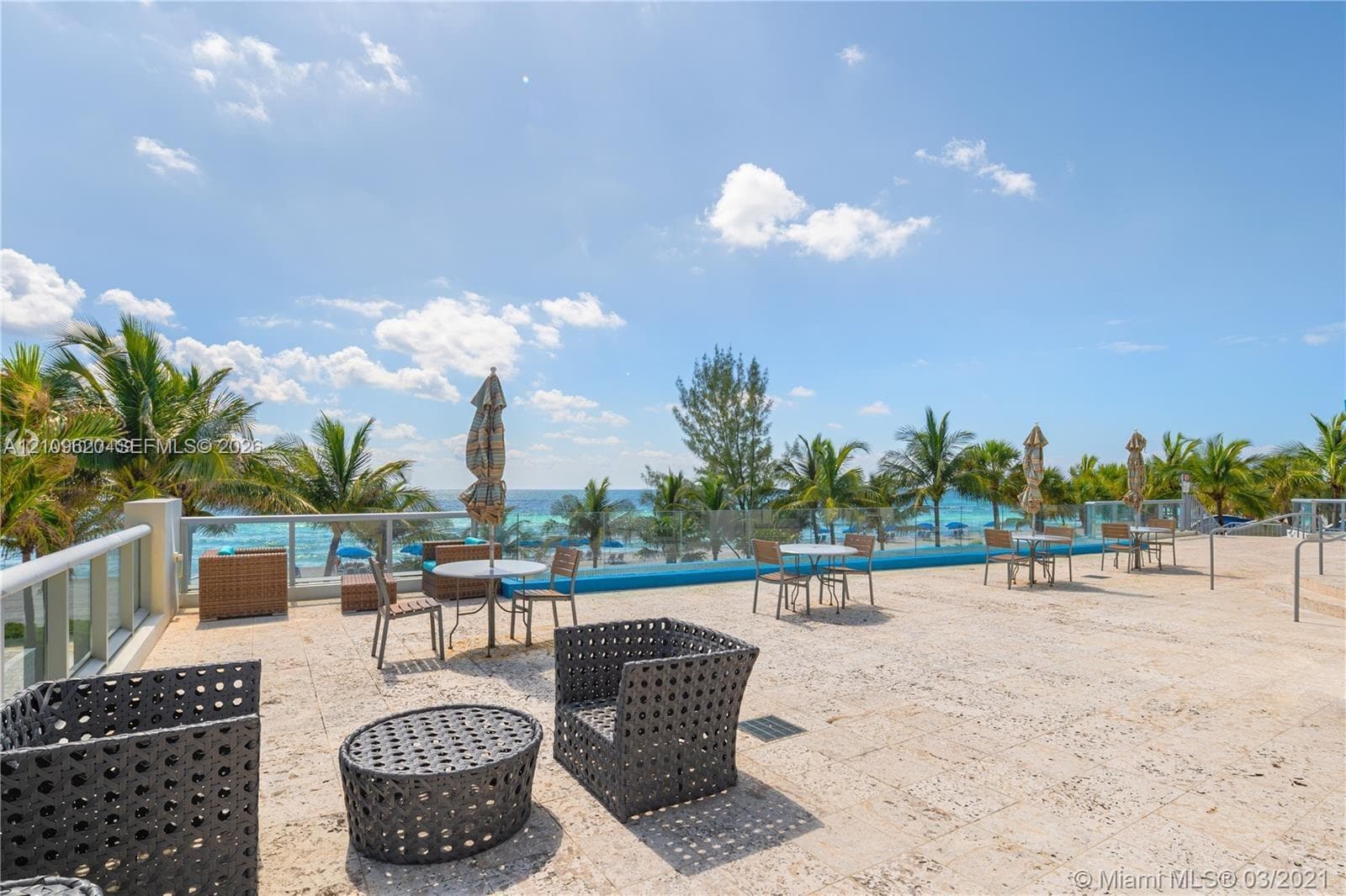 Expansive stone-paved terrace featuring a glass-panel railing and horizon-line water backdrop
