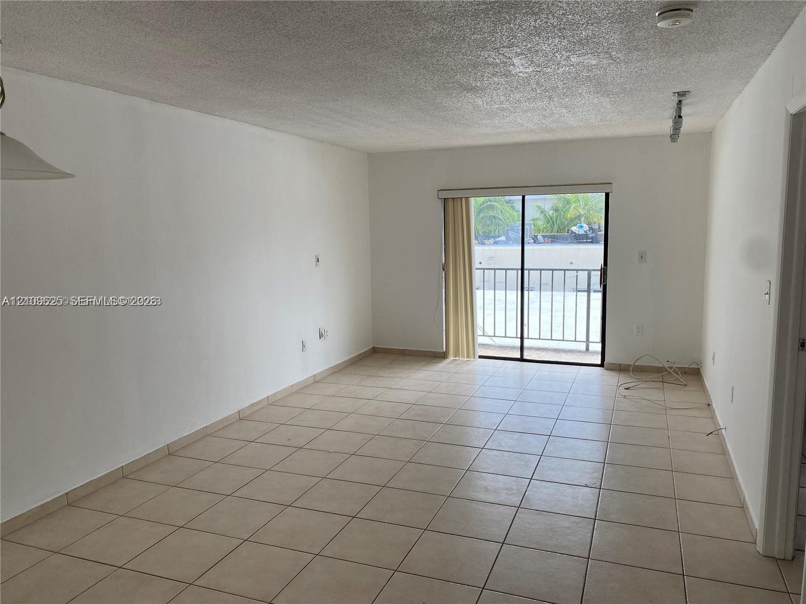Living area featuring tile flooring, neutral walls, and a sliding glass door with access to a railed balcony