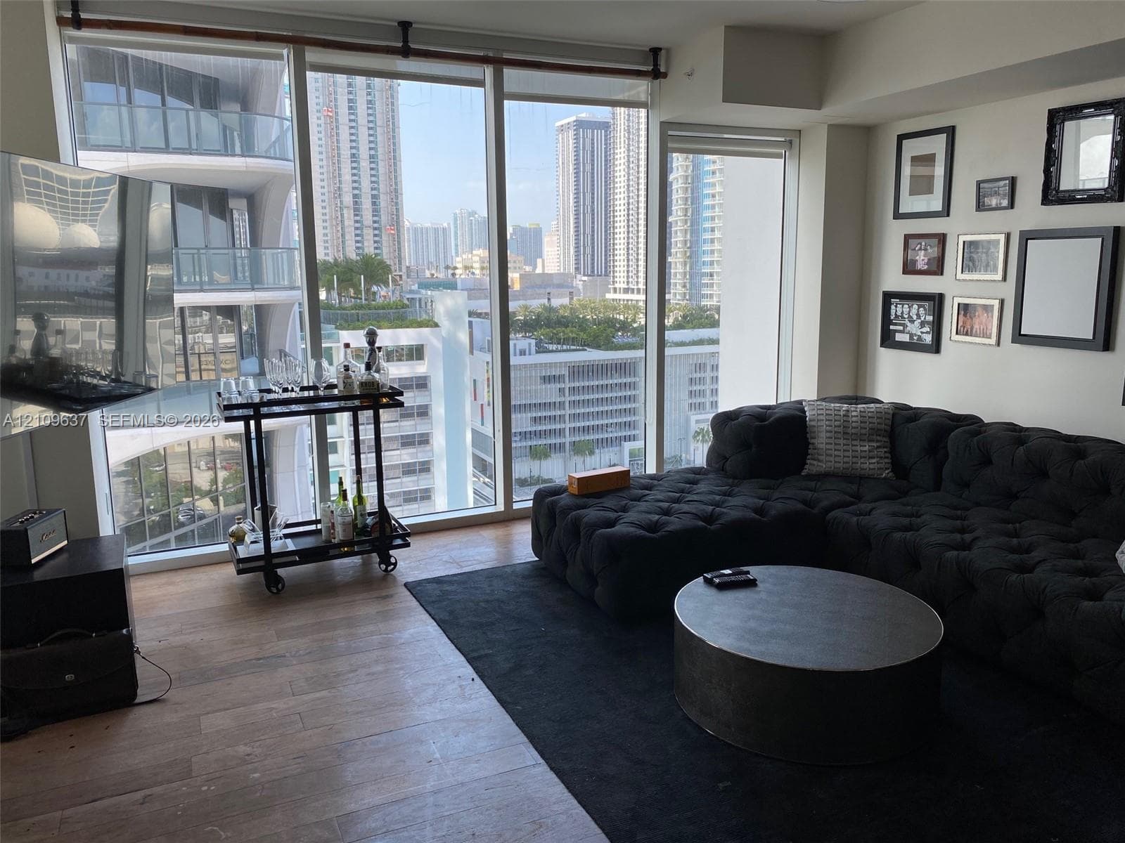 Floor-to-ceiling windows, wood-finish flooring, and high-rise urban surroundings