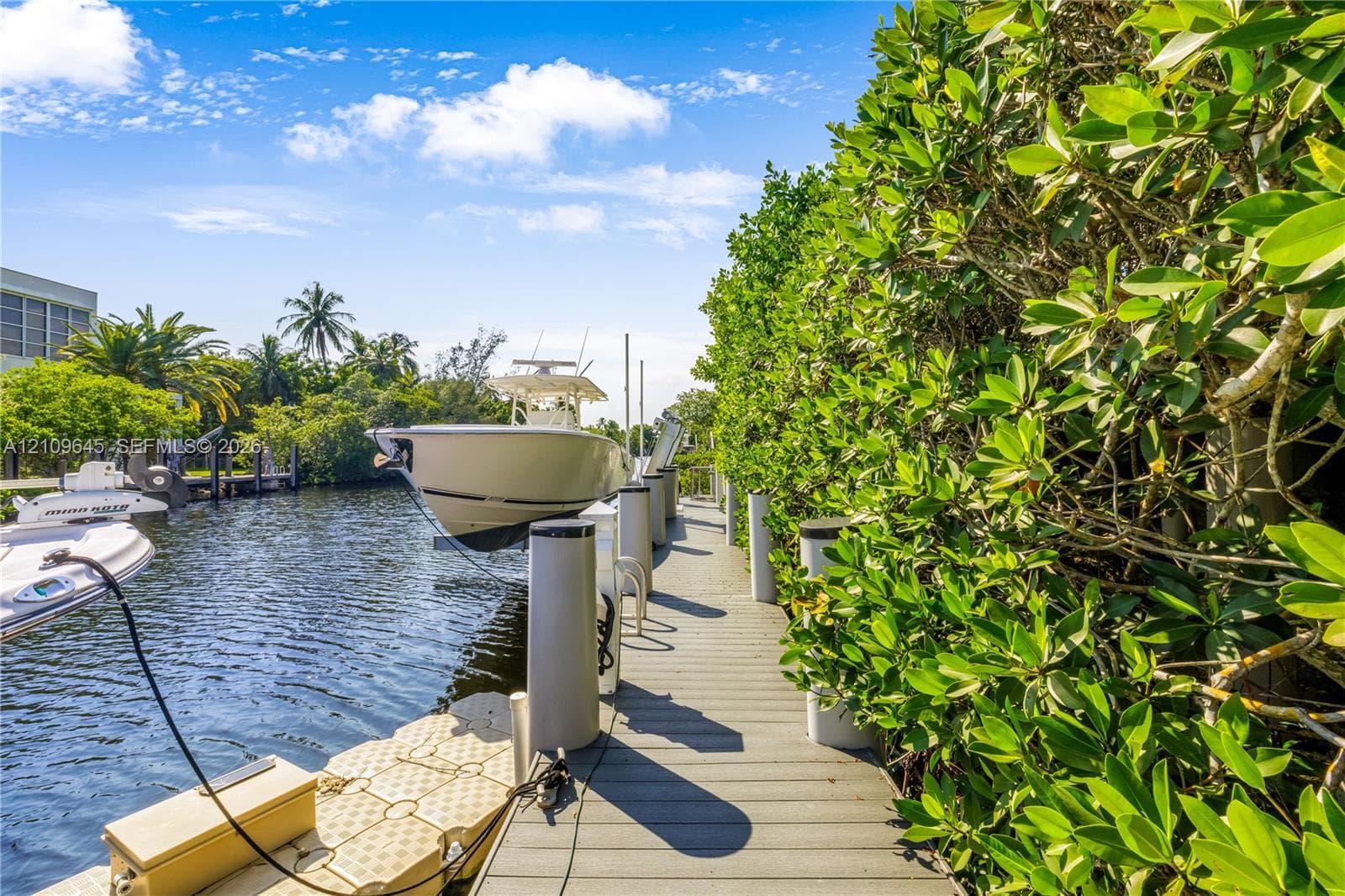 Waterfront dock featuring composite decking, vertical pilings, and a floating platform