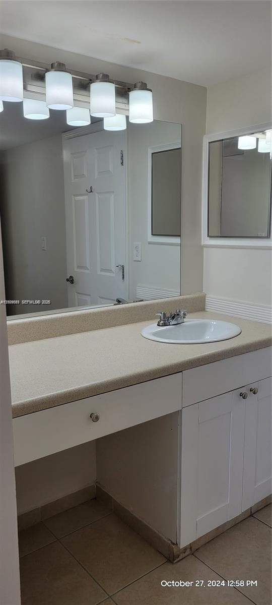 Bathroom vanity featuring white cabinetry, a solid-surface countertop, an integrated oval basin, and a four-light fixture