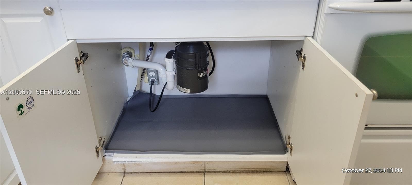 Cabinetry featuring white shaker-style doors, equipped with a heavy-duty garbage disposal and a protective floor mat