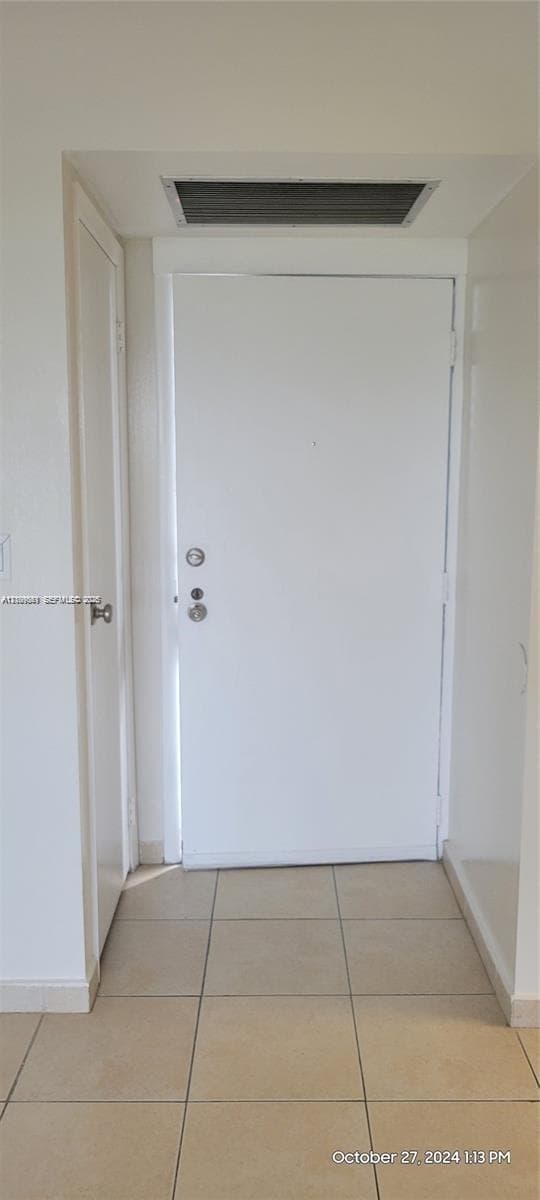 Entryway featuring a solid-core door with metallic deadbolt hardware and square ceramic tile flooring