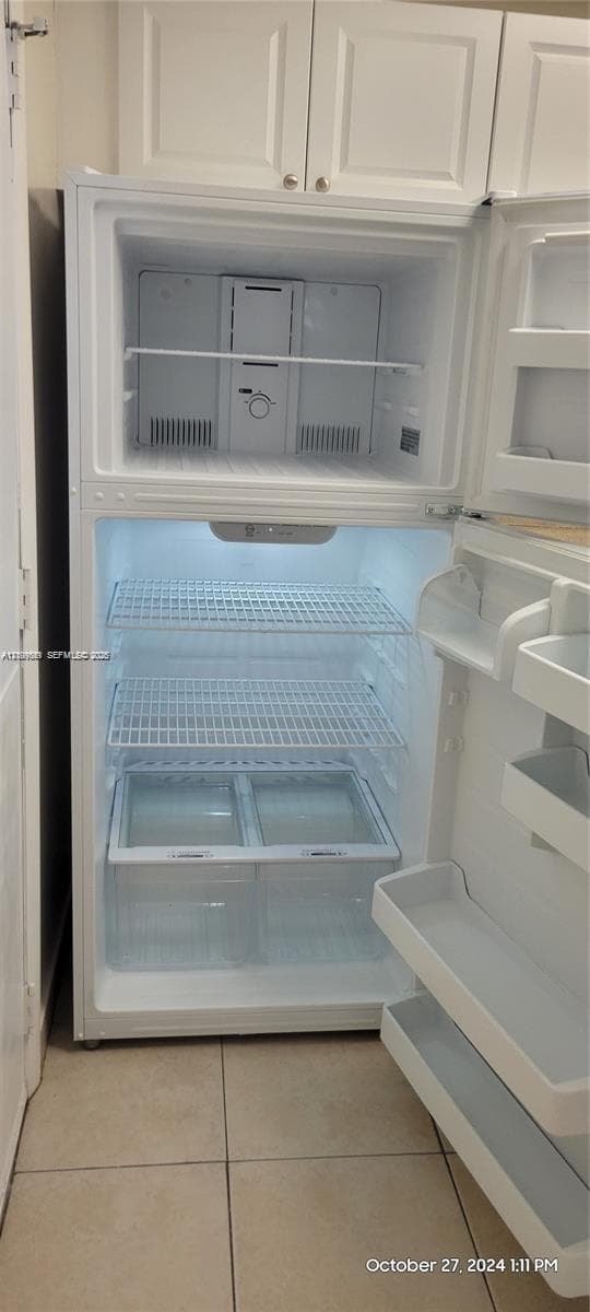 Top-mount refrigerator with wire shelving, integrated crisper drawers, and white shaker-style upper cabinetry