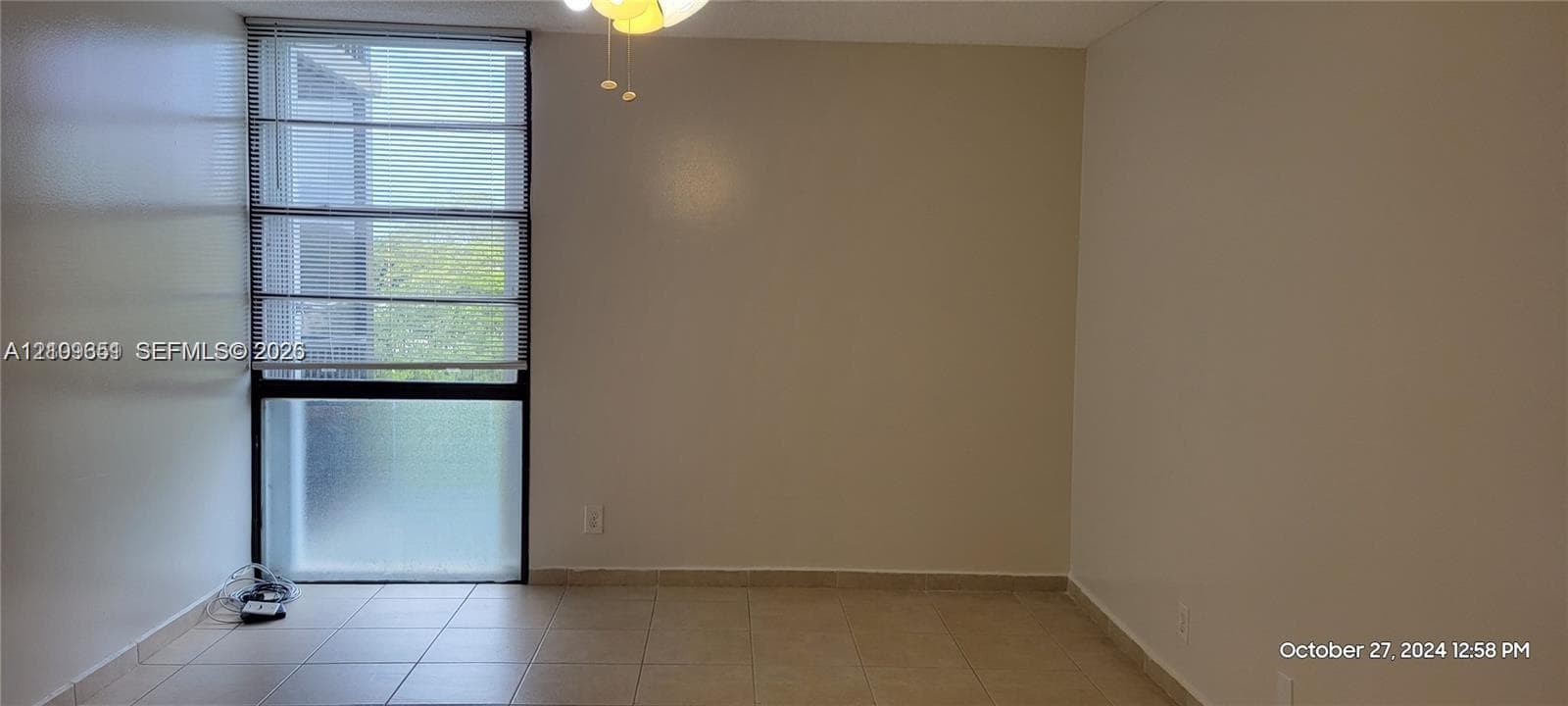 Interior space featuring neutral-toned walls, tile flooring, a floor-to-ceiling multi-pane window, and a ceiling-mounted light fixture