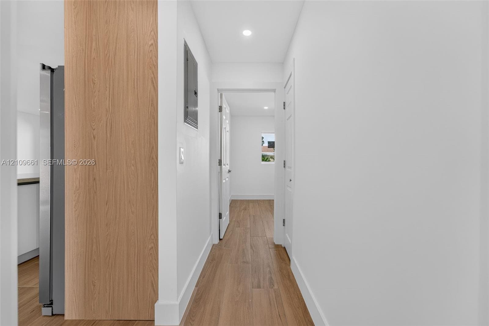Hallway featuring wood-finish flooring, recessed lighting, and white paneled interior doors