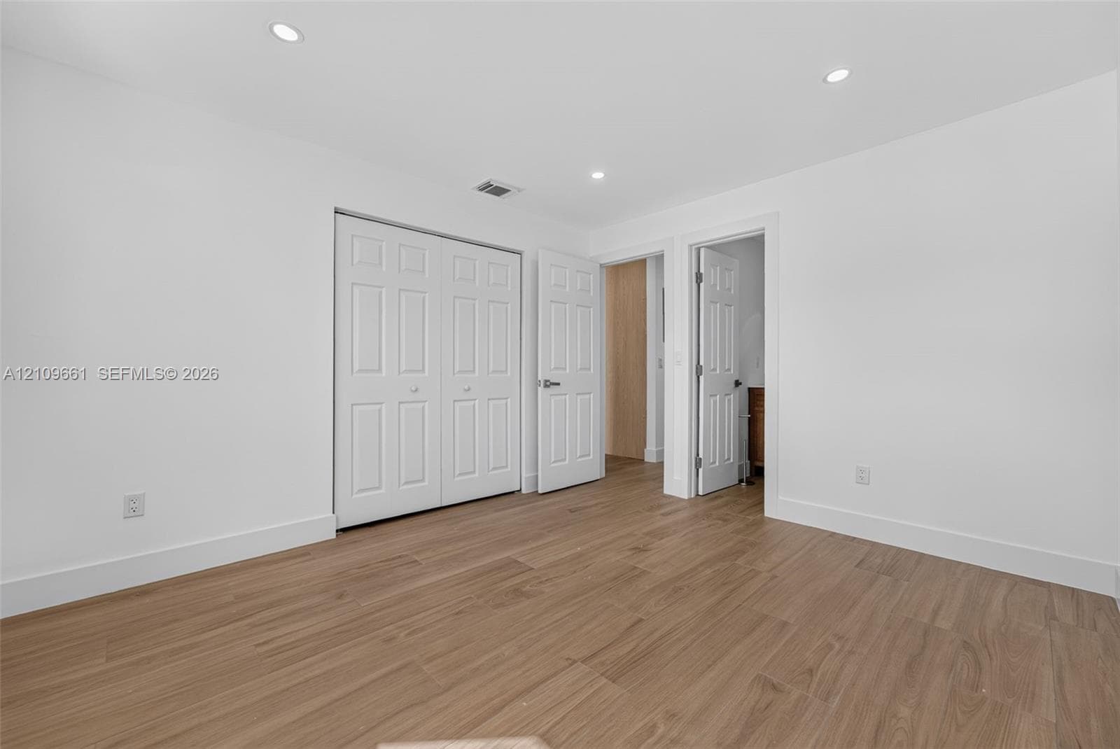 Interior space featuring wood-finish flooring, recessed lighting, and multi-panel interior doors