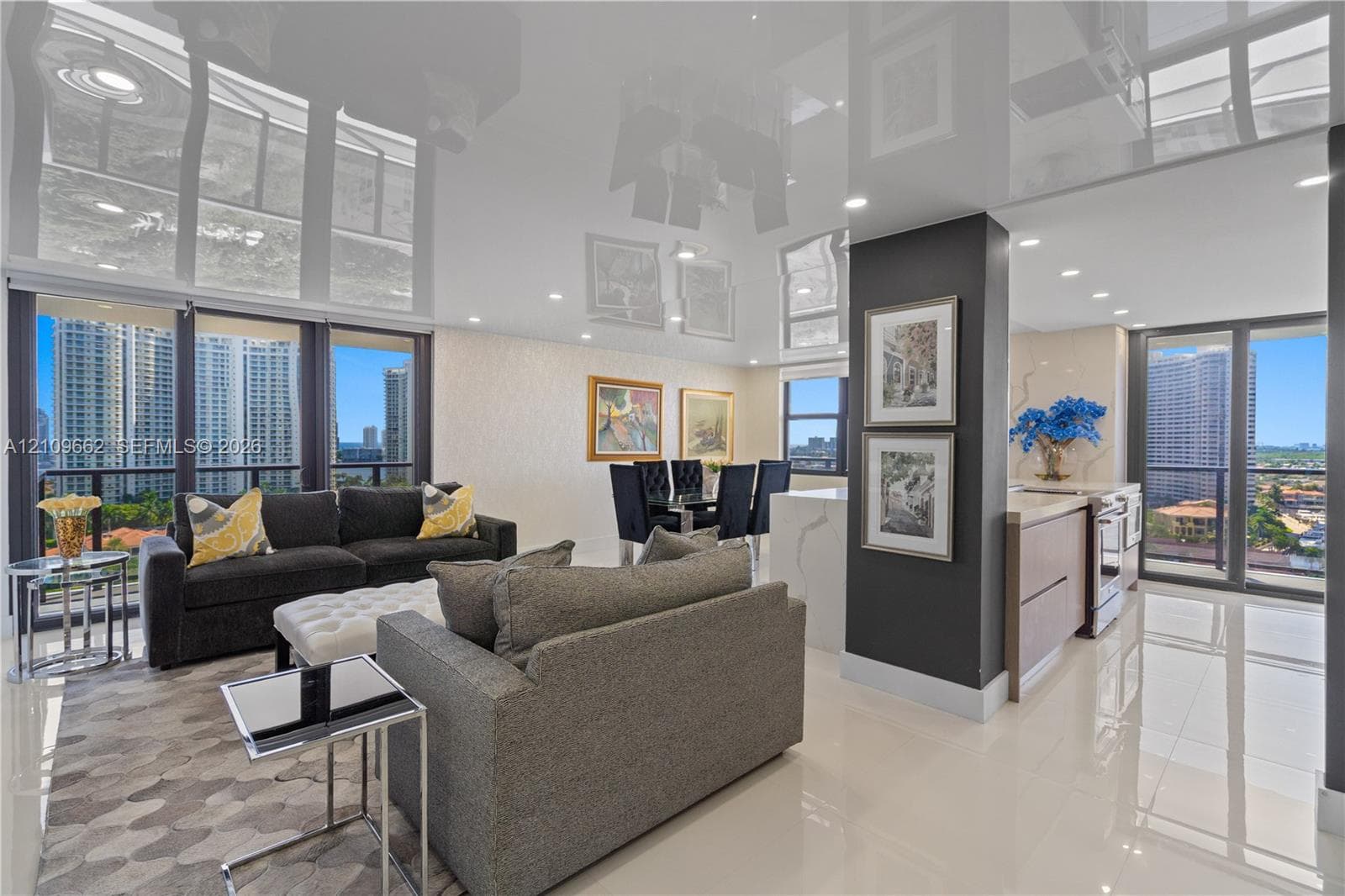 High-gloss reflective ceiling, expansive floor-to-ceiling windows, polished tile flooring, recessed lighting, and kitchen peninsula featuring stone-finish countertop