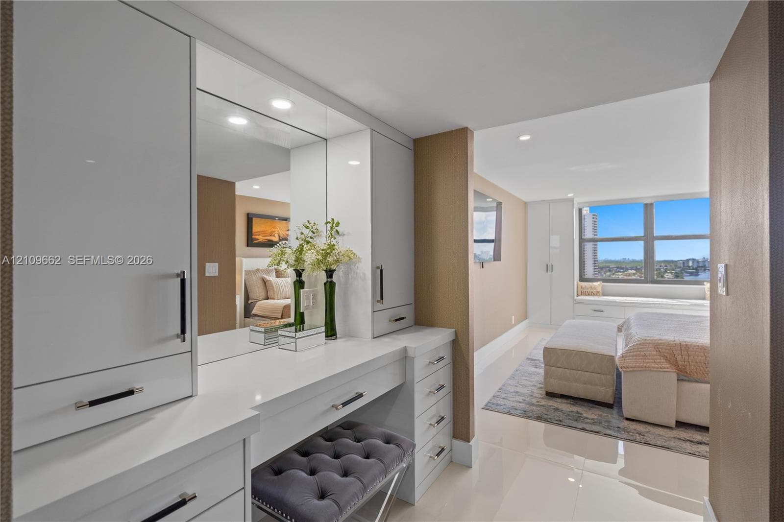 Built-in vanity featuring high-gloss cabinetry, stone countertops, integrated mirror, and polished metal hardware