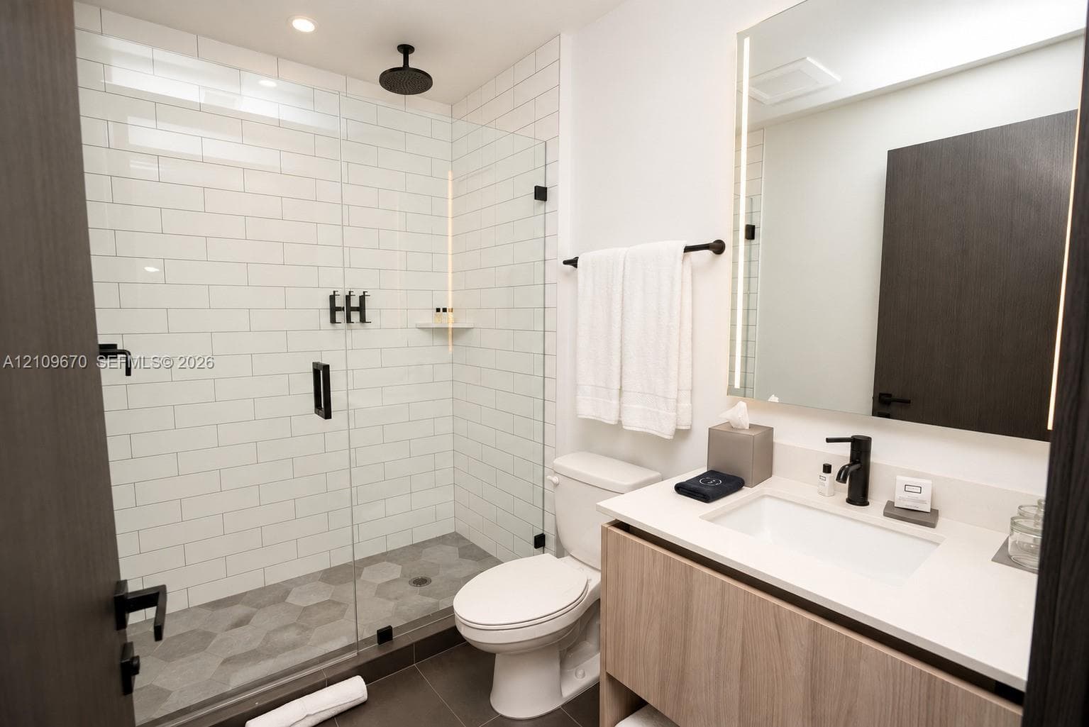 Walk-in shower with white subway tile, glass enclosure, and matte black rain-style showerhead
