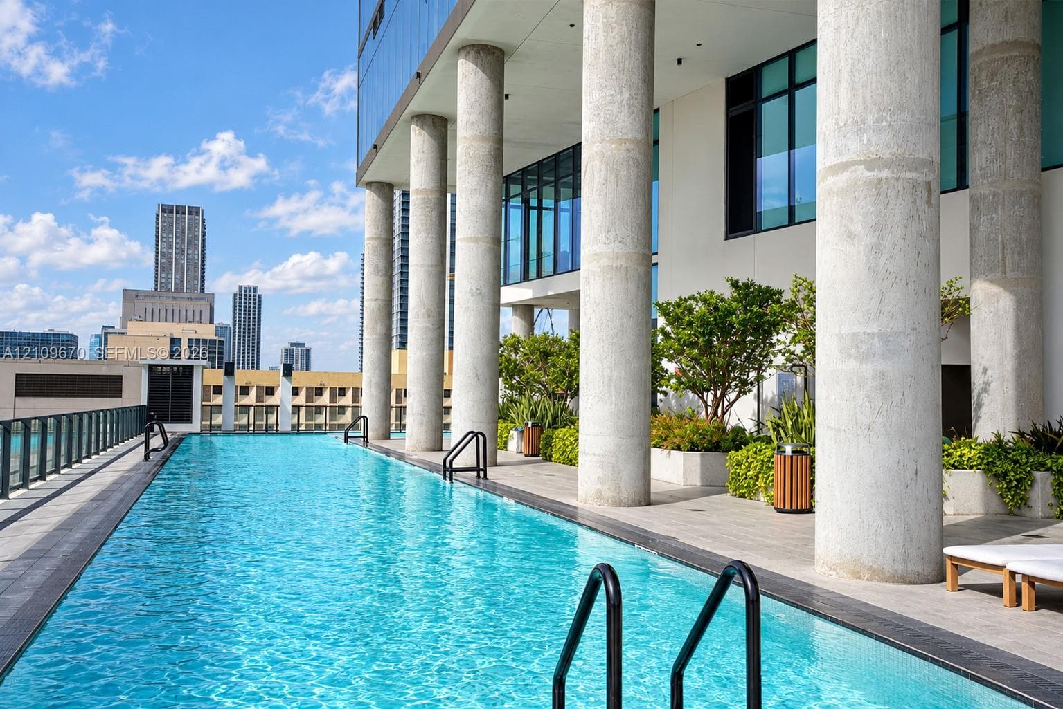 Swimming pool featuring a tiled deck, concrete support columns, built-in planters, and metal handrails