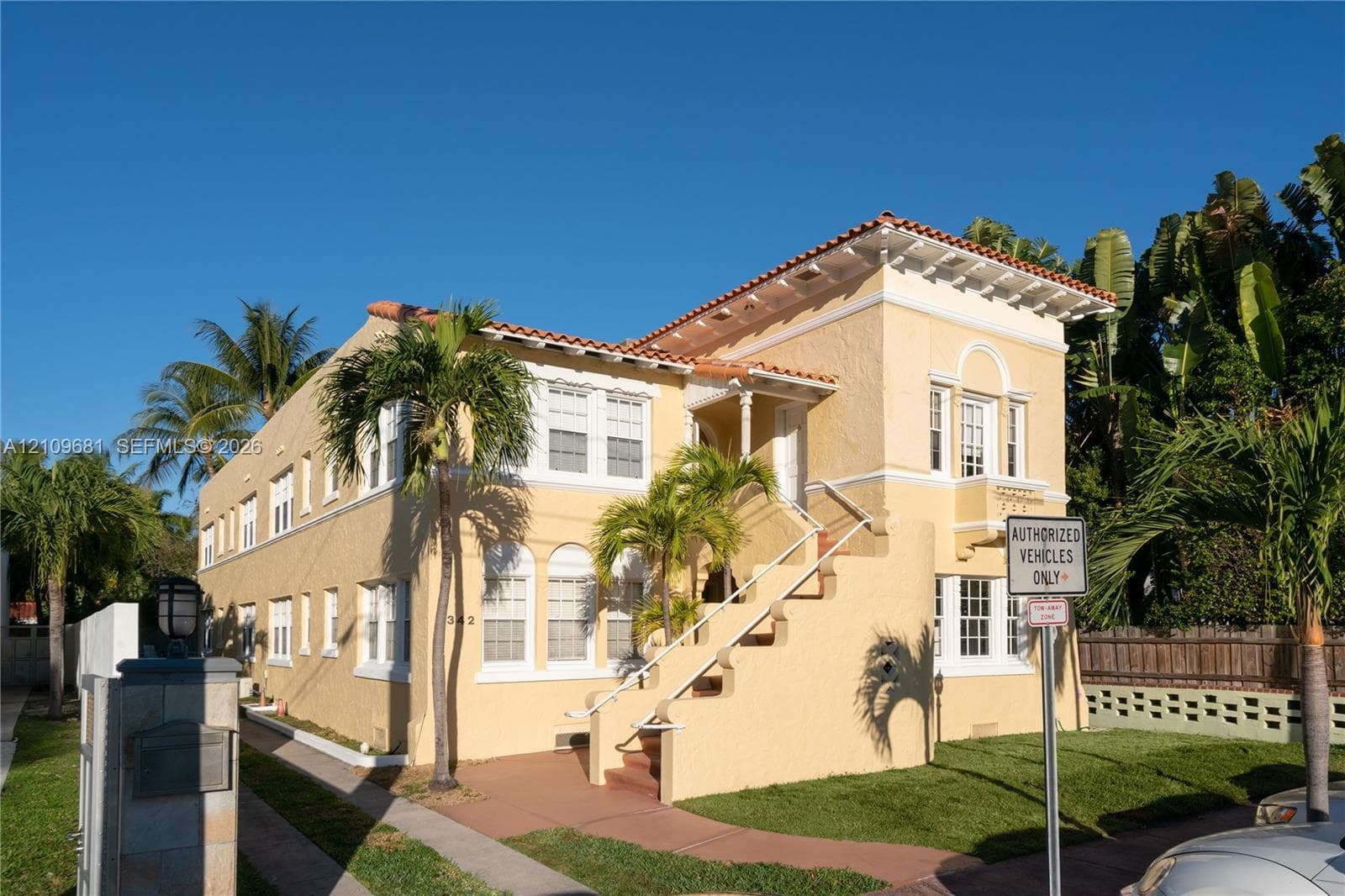 Mediterranean-style exterior featuring a stucco facade, clay tile roof, decorative corbels, arched window detailing, and an exterior concrete staircase