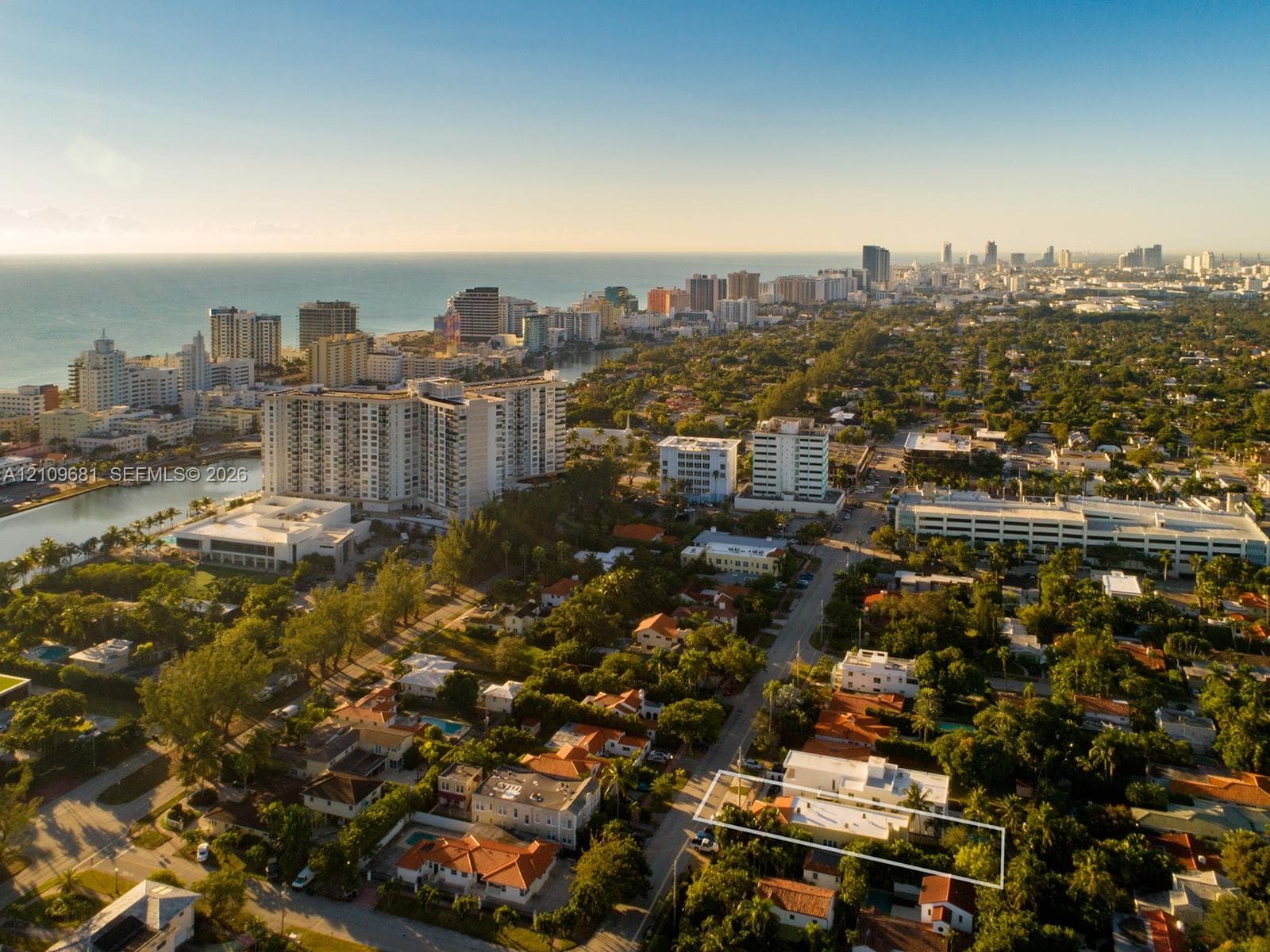 Aerial perspective of residential property featuring mature trees and proximity to the coastline and urban center