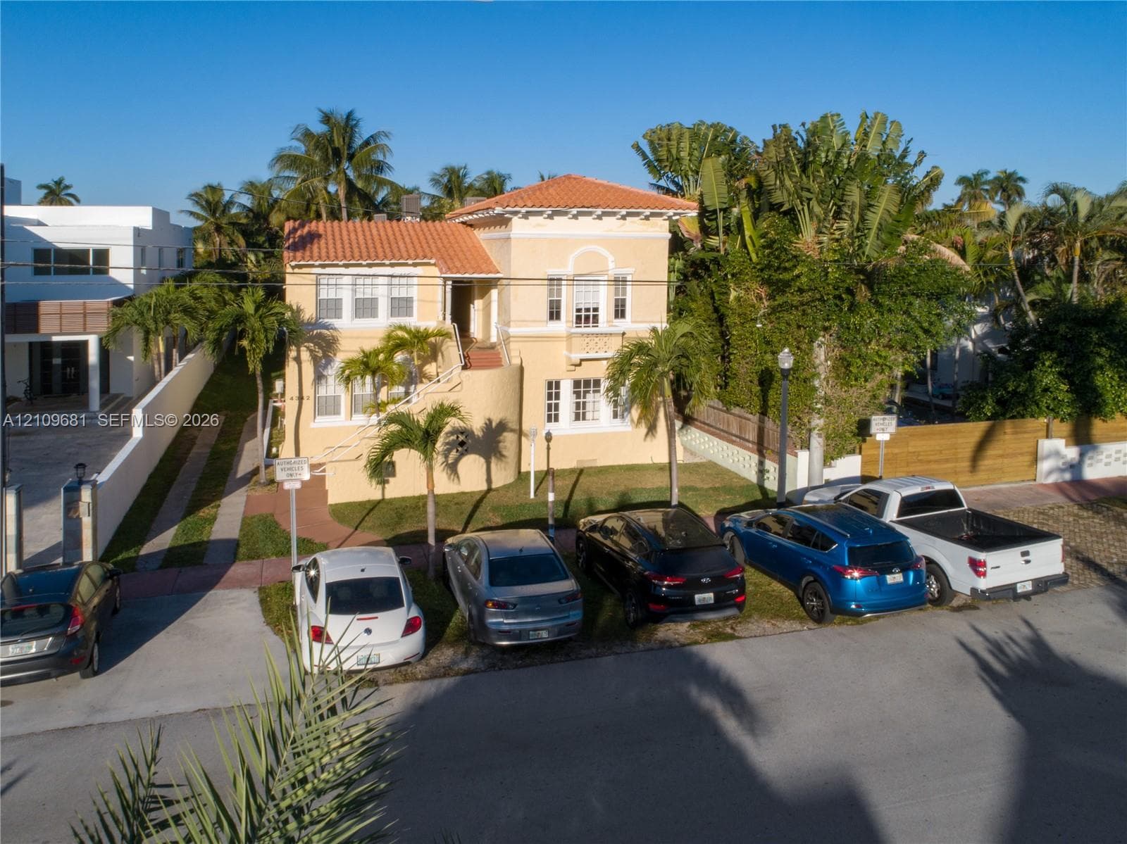 Mediterranean-style exterior featuring a clay tile roof, stucco finish, multi-pane windows, and a curved staircase