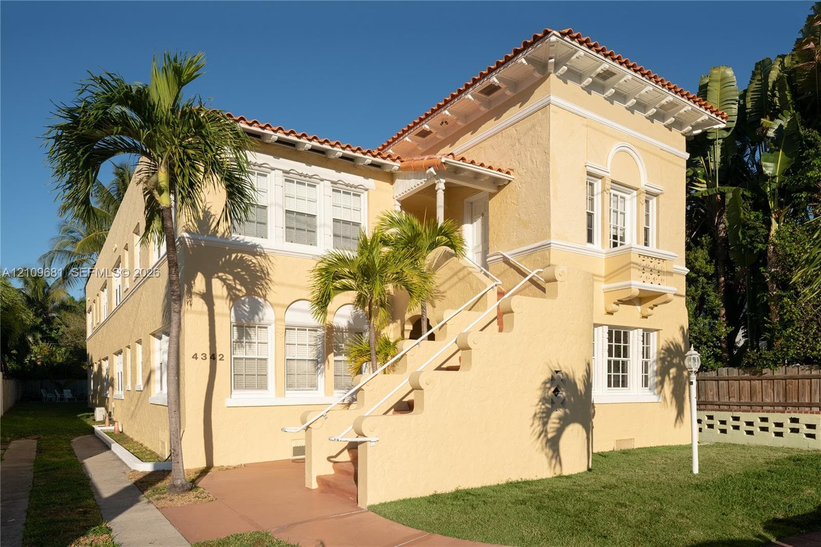 Mediterranean-style exterior featuring a clay tile roof, stucco finish, arched window detailing, an external staircase with decorative railings, and a balcony with balustrades