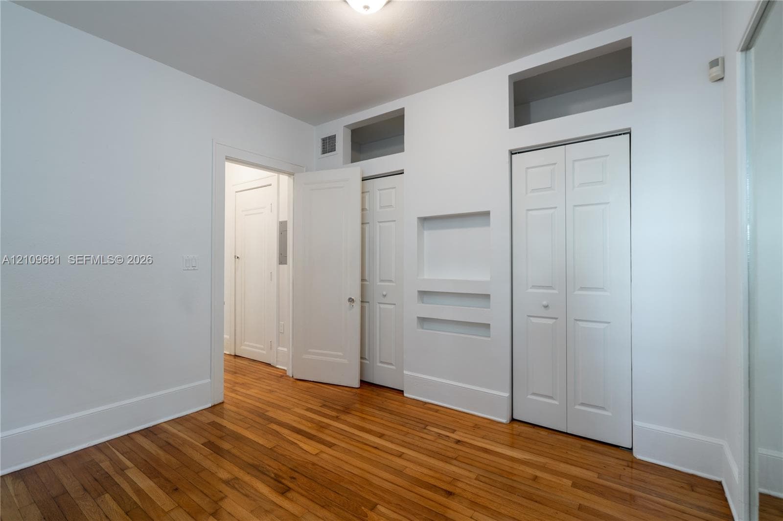 Wood-finish flooring, multi-panel closet doors, built-in recessed shelving, and high-set transom windows