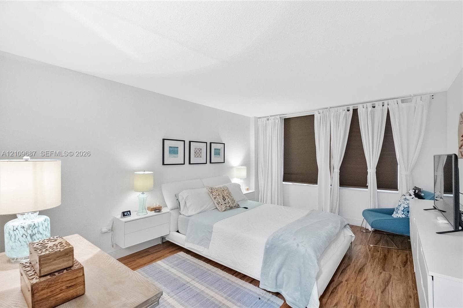 Wood-finish flooring, neutral wall tones, and large windows with integrated blinds
