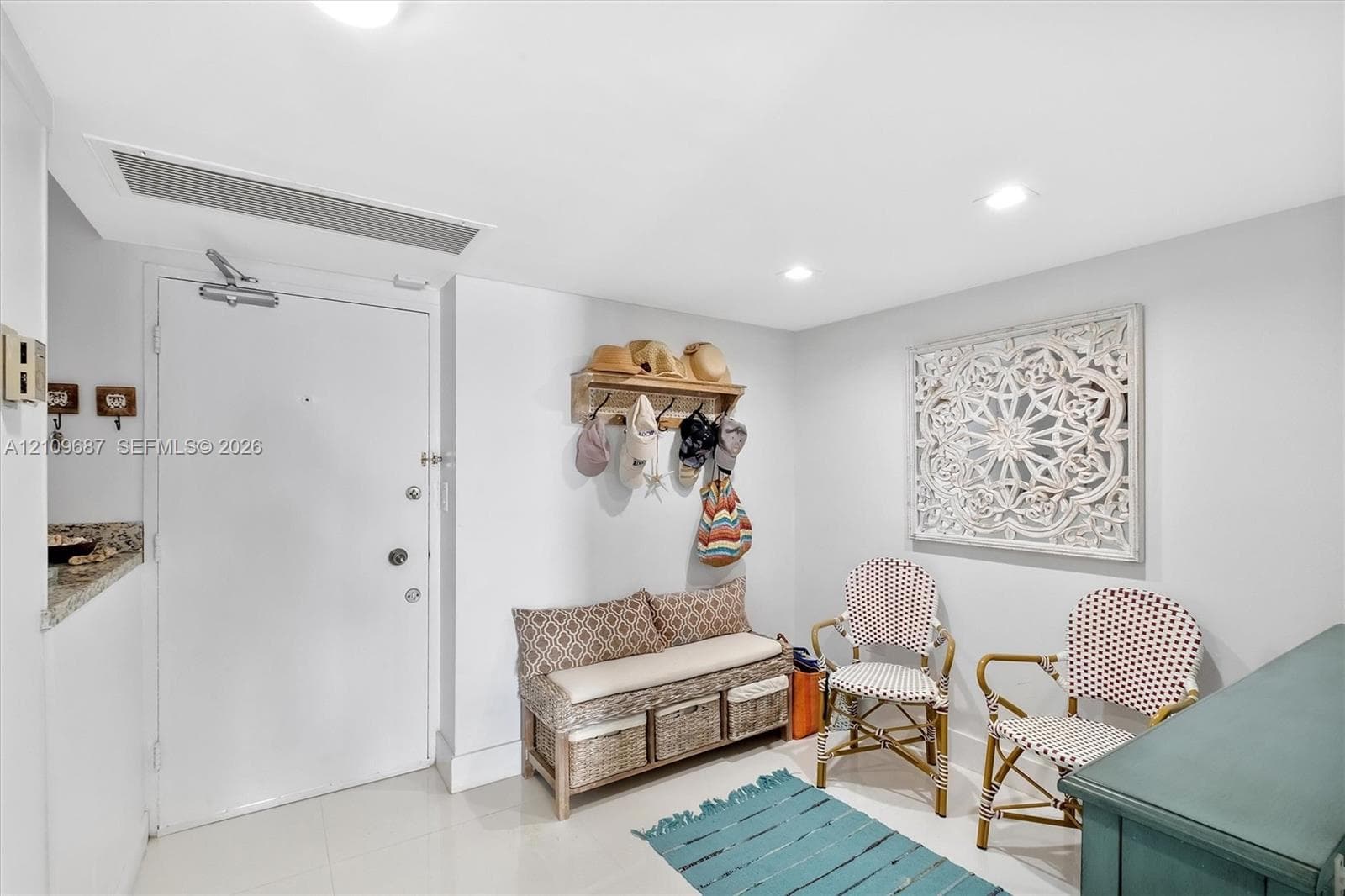 Entryway featuring recessed ceiling lighting, neutral tile flooring, and a wall-mounted wooden coat rack