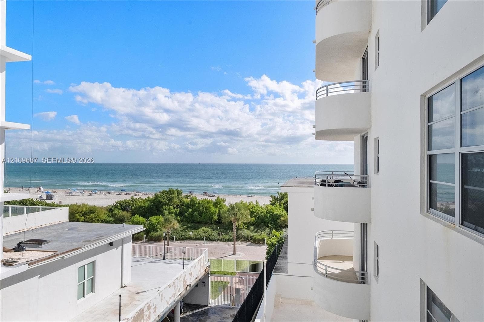 Stacked semi-circular balconies with metal railings, white stucco exterior, and oceanfront proximity