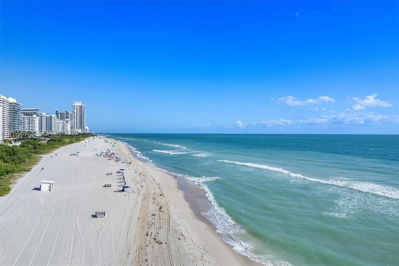 Coastal landscape featuring an expansive sandy shoreline and ocean waves