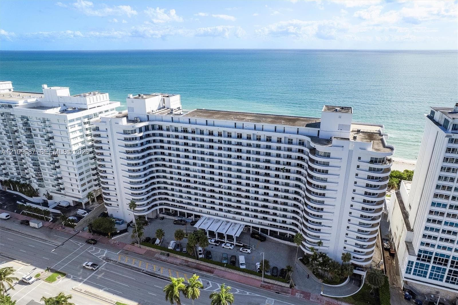 High-rise residential building featuring a curved architectural design, continuous private balconies, and a direct oceanfront location