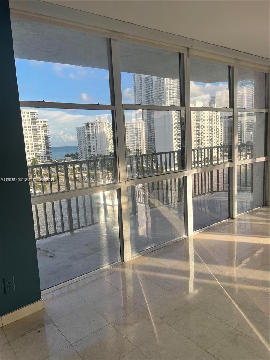 Floor-to-ceiling windows featuring aluminum frames, polished tile flooring, and a private balcony with metal railing