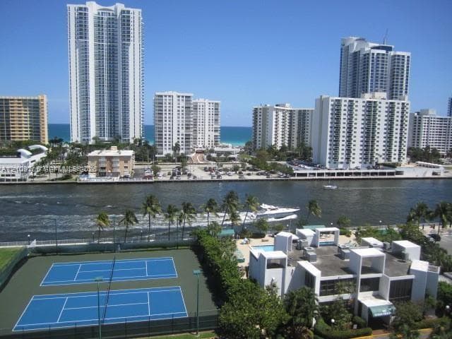 Waterfront property grounds featuring dual hard-surface tennis courts, an outdoor swimming pool, and direct access to a navigable waterway