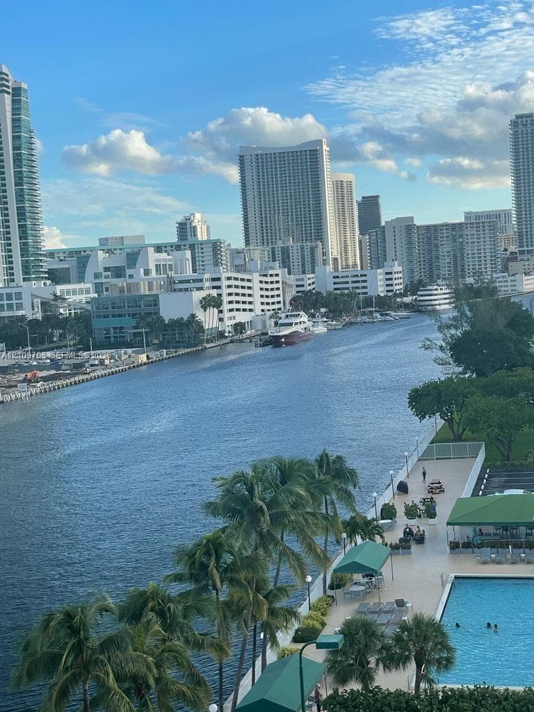 Waterfront property featuring a swimming pool, paved sundeck, palm tree landscaping, and a direct maritime waterway