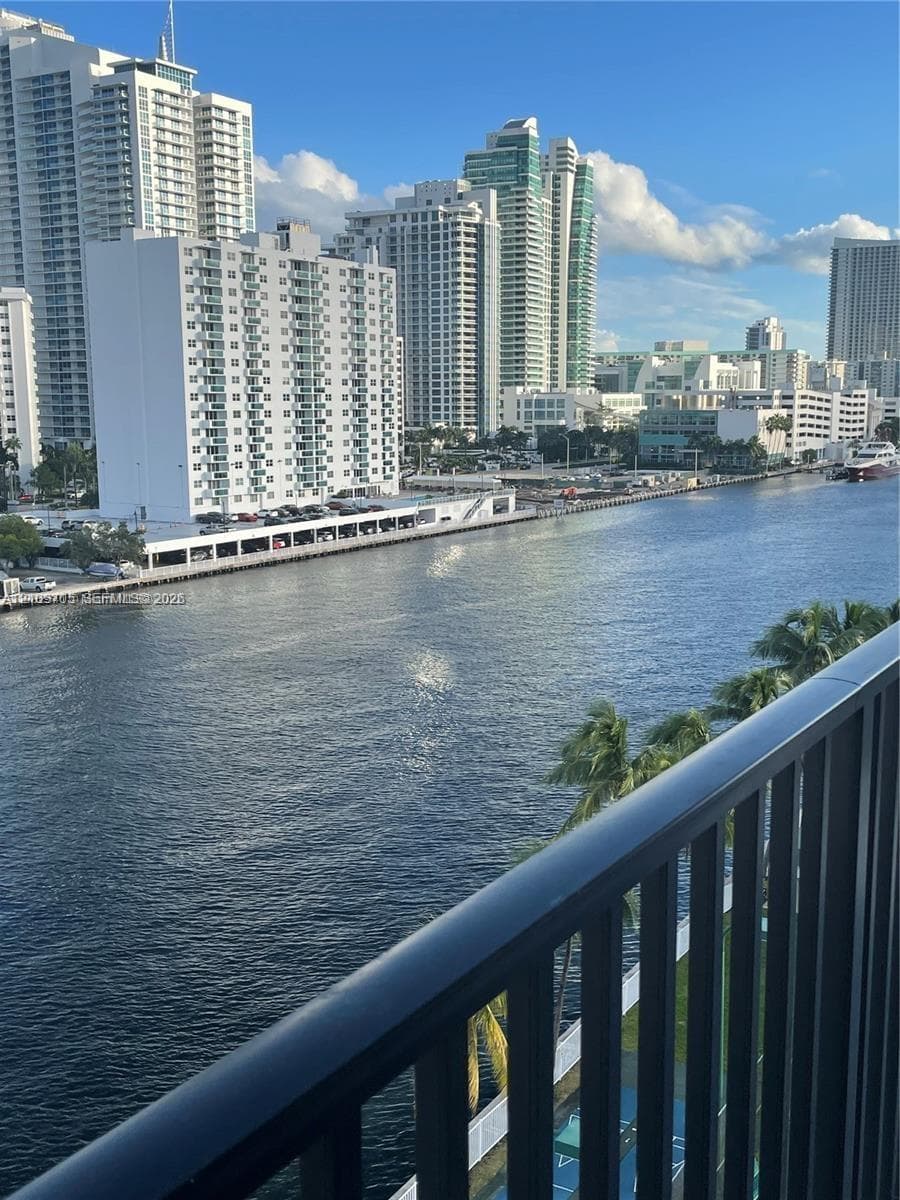 Balcony with a black metal railing overlooking the waterway and high-rise skyline