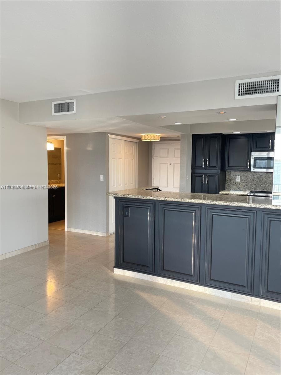 Kitchen featuring dark cabinetry, stone-surface breakfast bar, recessed lighting, and tile flooring